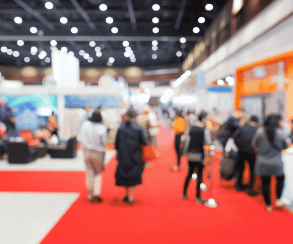 Tendências para eventos corporativos: público circulando por feira com estandes, ativações de marca e espaços de networking em pavilhão moderno.