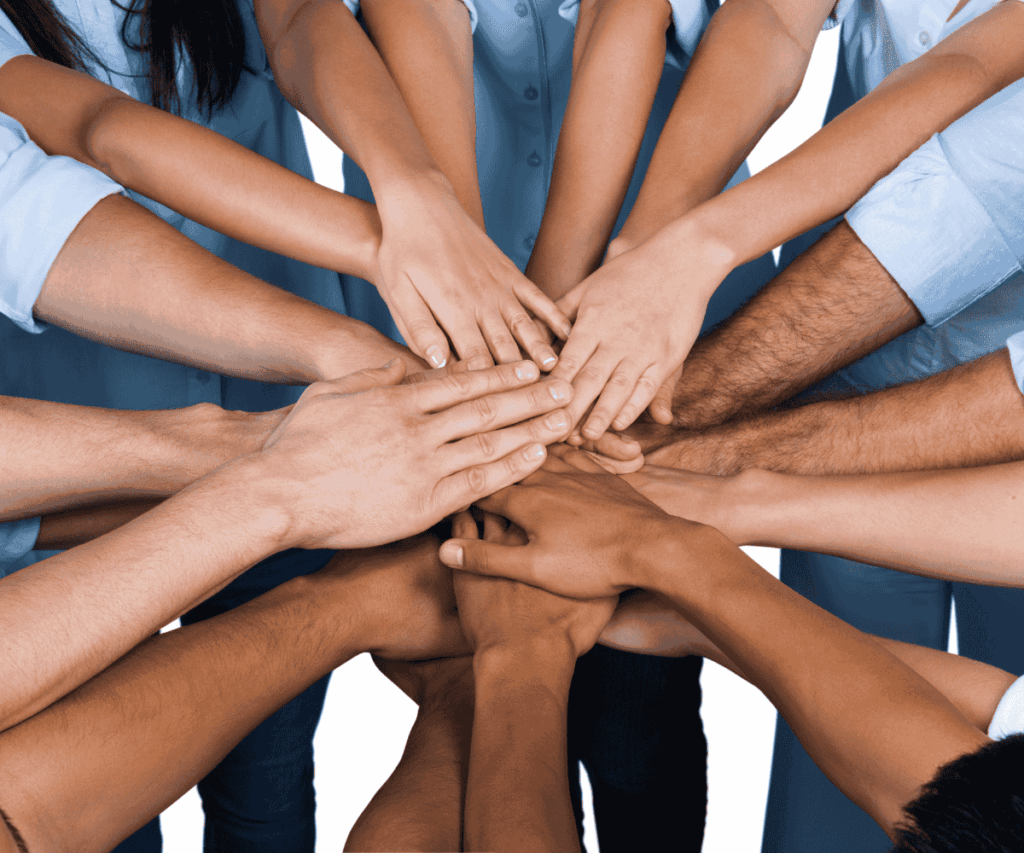 Grupo de pessoas com diferentes tons de pele unindo as mãos, representando colaboração, diversidade e conexão humana.