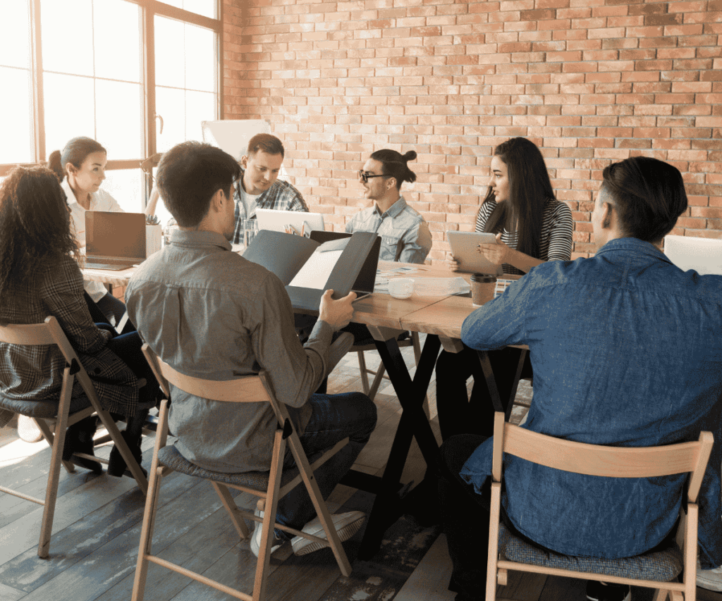 Fotos para artigos antigos (30) Grupo de profissionais reunidos em uma mesa de reunião, discutindo ideias e analisando materiais, em um ambiente corporativo.